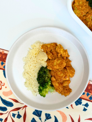 Photo d'un délicieux plat de poulet au beurre servi avec du riz basmati, du brocoli croquant et du chou-fleur, le tout nappé d'une sauce parfumée et légèrement épicée. Découvrez le chez Appétit Go.