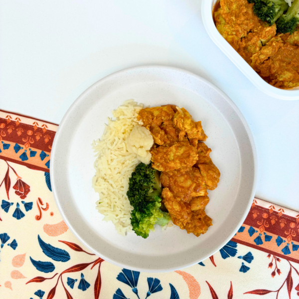 Photo d'un délicieux plat de poulet au beurre servi avec du riz basmati, du brocoli croquant et du chou-fleur, le tout nappé d'une sauce parfumée et légèrement épicée. Découvrez le chez Appétit Go.