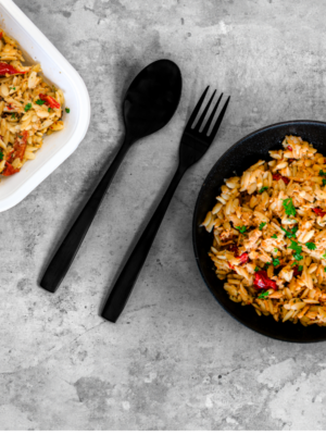 Image d'orzo crémeux au poulet et tomates séchées présenté dans une assiette et un contenant de repas rapide. Prêt à être cuisiné et dégusté.